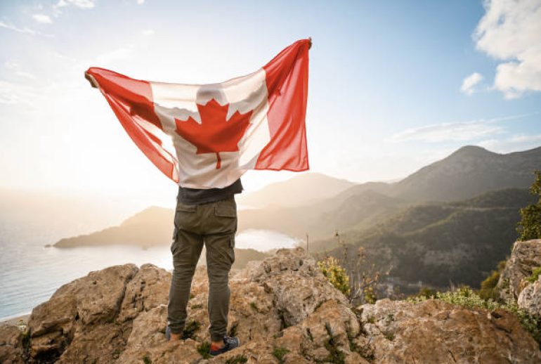 man with Canadian flag on the background of the sea and mountains